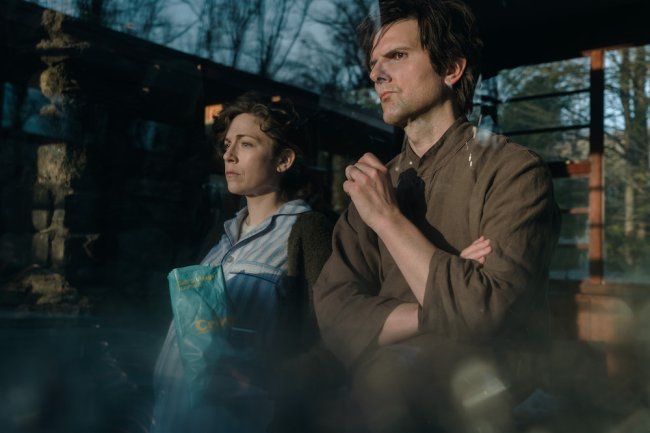 Medium shot of a man and woman looking at something unseen at dusk in the woods; still from "Severance."