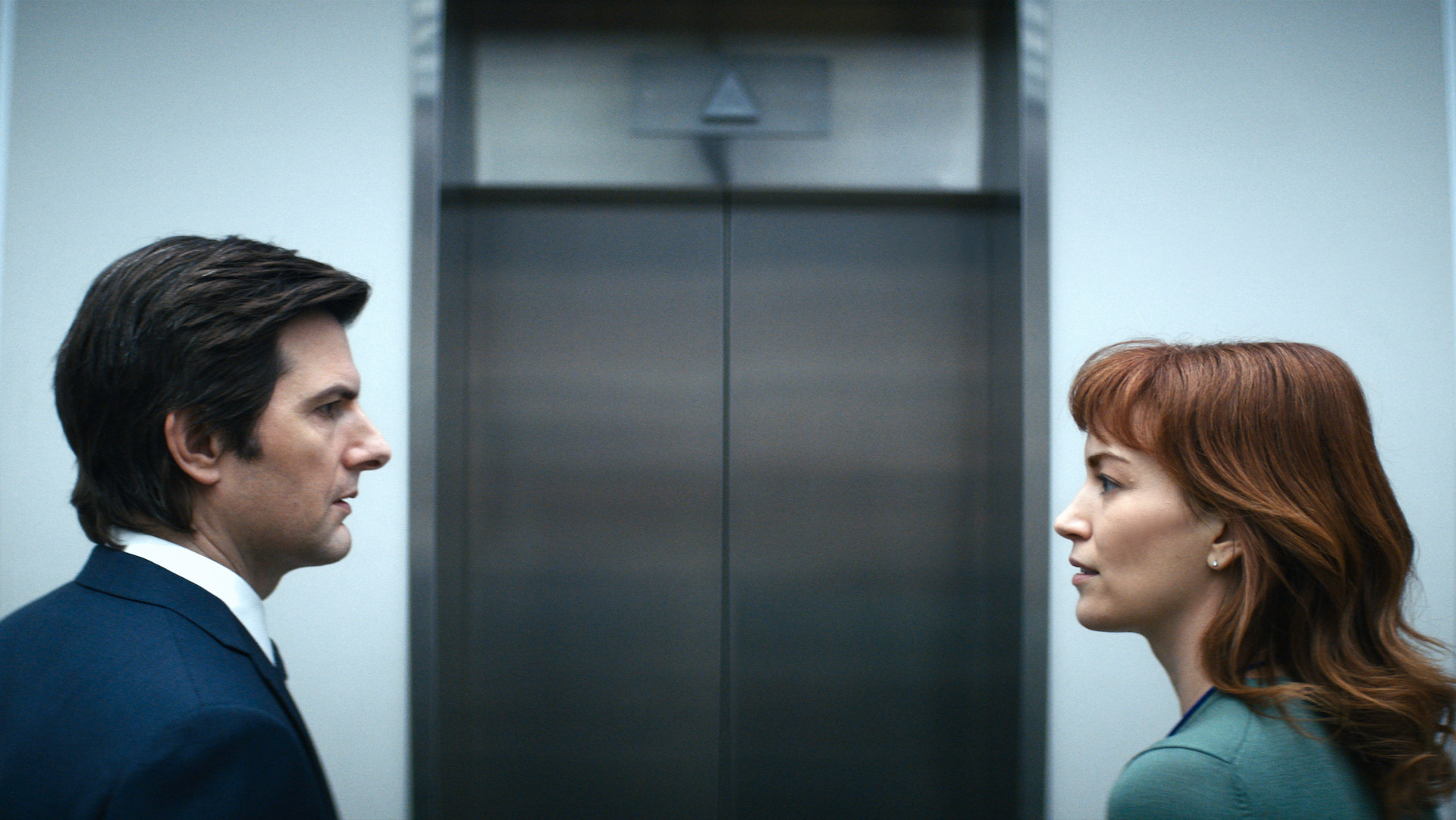 A man and woman facing each other outside a closed elevator; still from 'Severance'