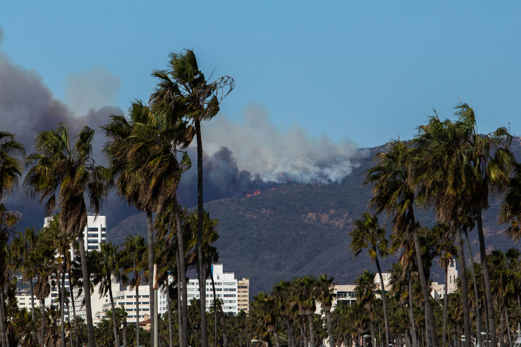 LOS ANGELES, CALIFORNIA - JANUARY 7: A firefighting aircraft drops the fire retardant Phos-Chek as the Palisades Fire burns amid a powerful windstorm on January 7, 2025 in the Pacific Palisades neighborhood of Los Angeles, California. The fast-moving wildfire is threatening homes in the coastal neighborhood amid intense Santa Ana Winds and dry conditions in Southern California. (Photo by Apu Gomes/Getty Images)