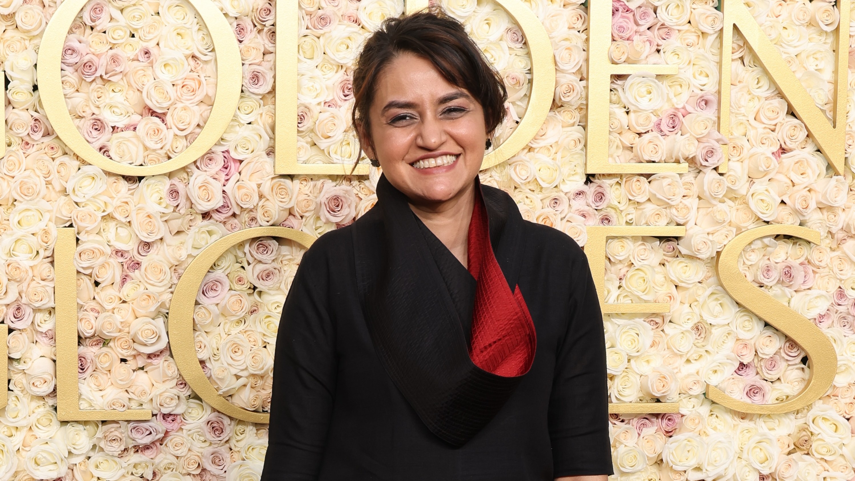 Payal Kapadia wearing a black shirt with deep red lining on the Golden Globes red carpet