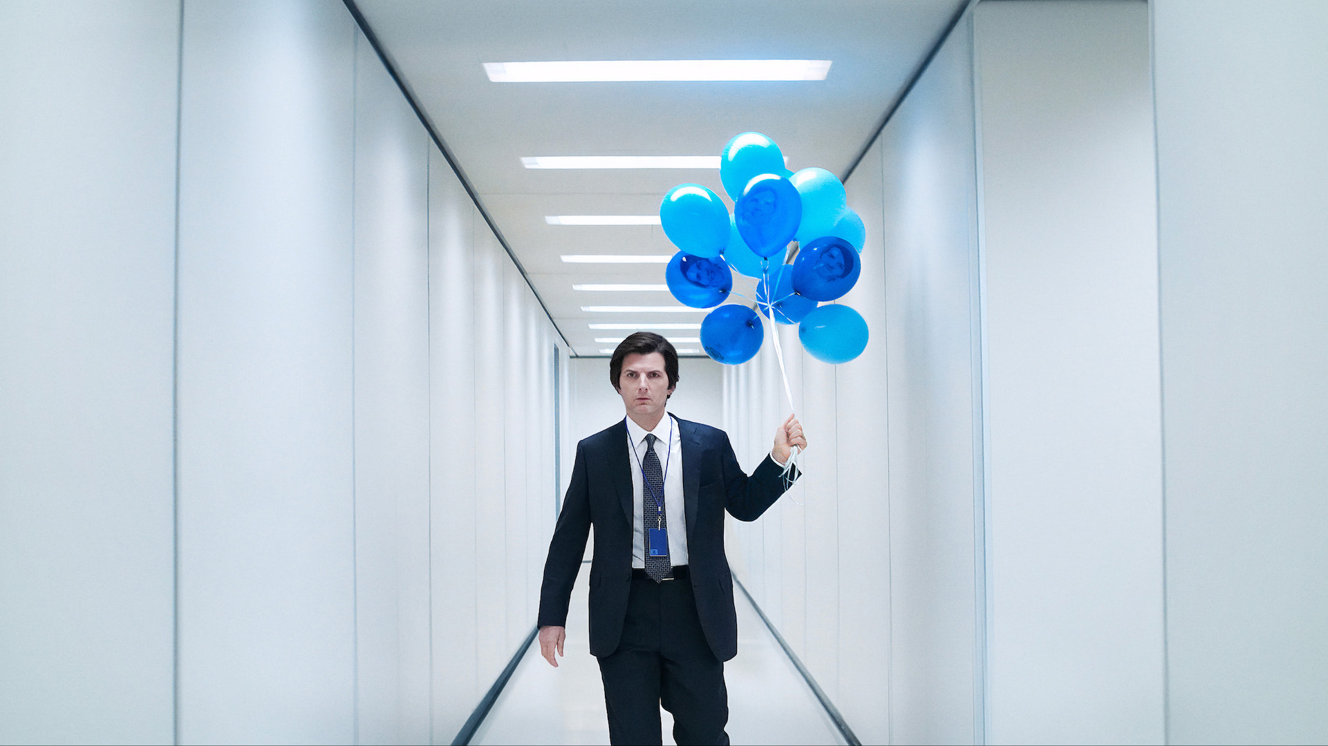 Adam Scott in 'Severance' holding blue balloons in an office hallway