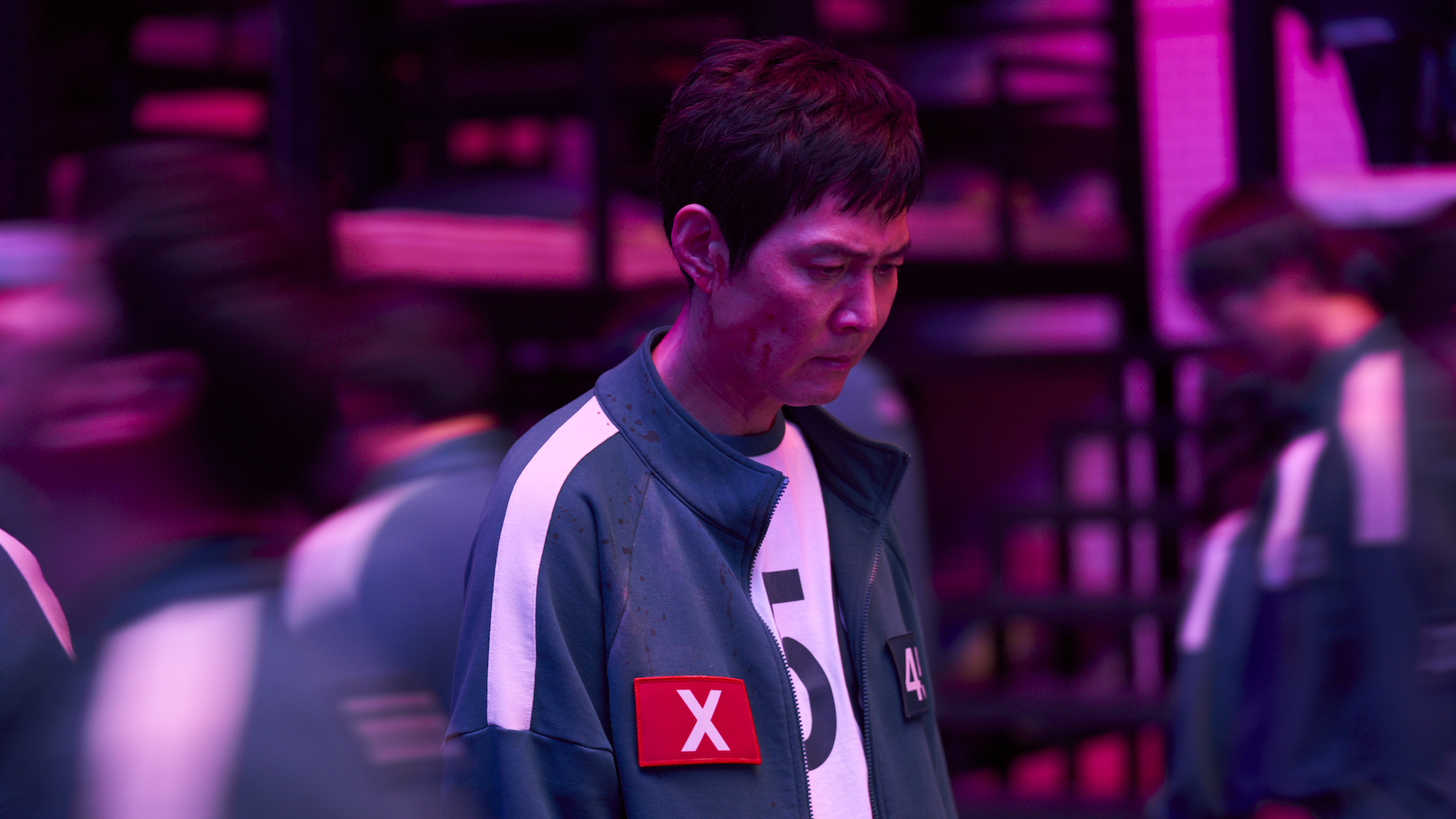 A man in a green and white tracksuit with a red X on the chest; Lee Jung-jae in 'Squid Game 2'